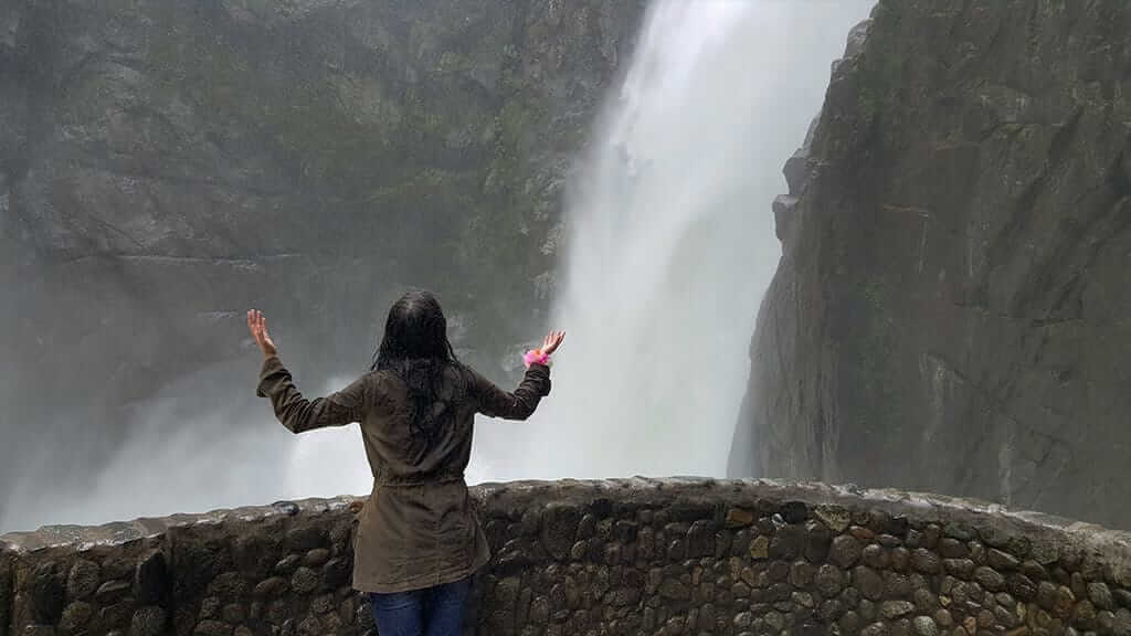 Mujer abrazando cascada spray en pailon del diablo banos ecuador