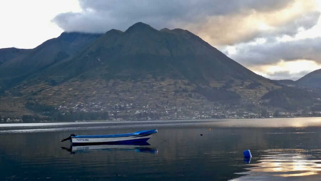 Ein Boot schwimmt auf dem San Pablo See vor dem Hintergrund des Vulkans Imbabura