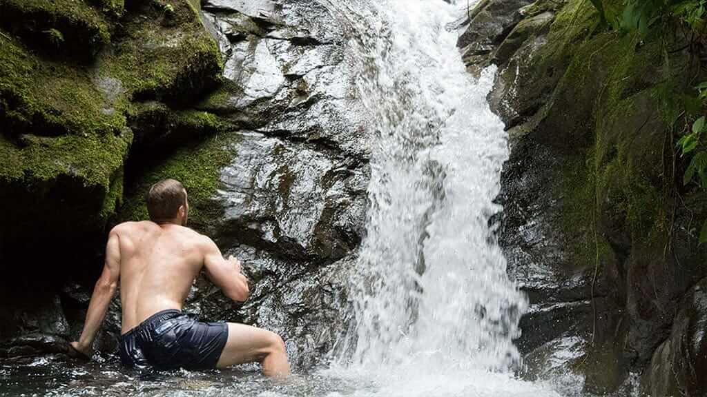 a tourist bathing under a waterfall at mindo ecuador