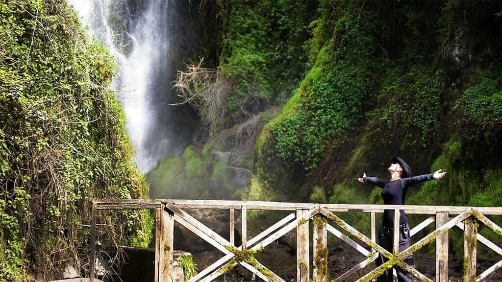 tourists embracing spray from ecuador waterfall