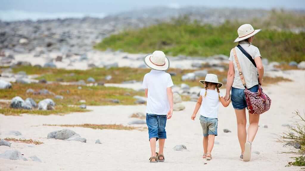 tour familiar en Galápagos - una madre y sus hijos caminando por la playa
