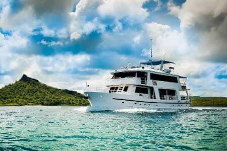 Fragata Yacht Galapagos Islands - zijaanzicht van de Fragata met groene eilandachtergrond