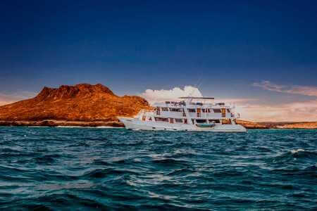 Die Monserrat-Yacht segelt bei Sonnenuntergang an Sombrero Chino Galapagos vorbei