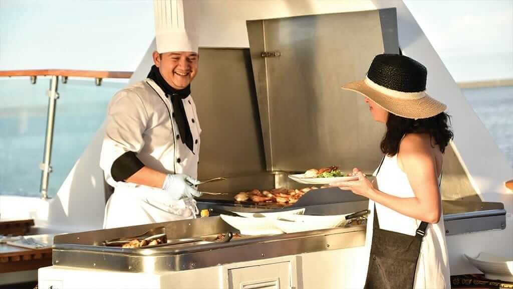 Coral 1 en 2 jachten galapagos cruises - chef-kok serveert lunch van de grill aan een toerist