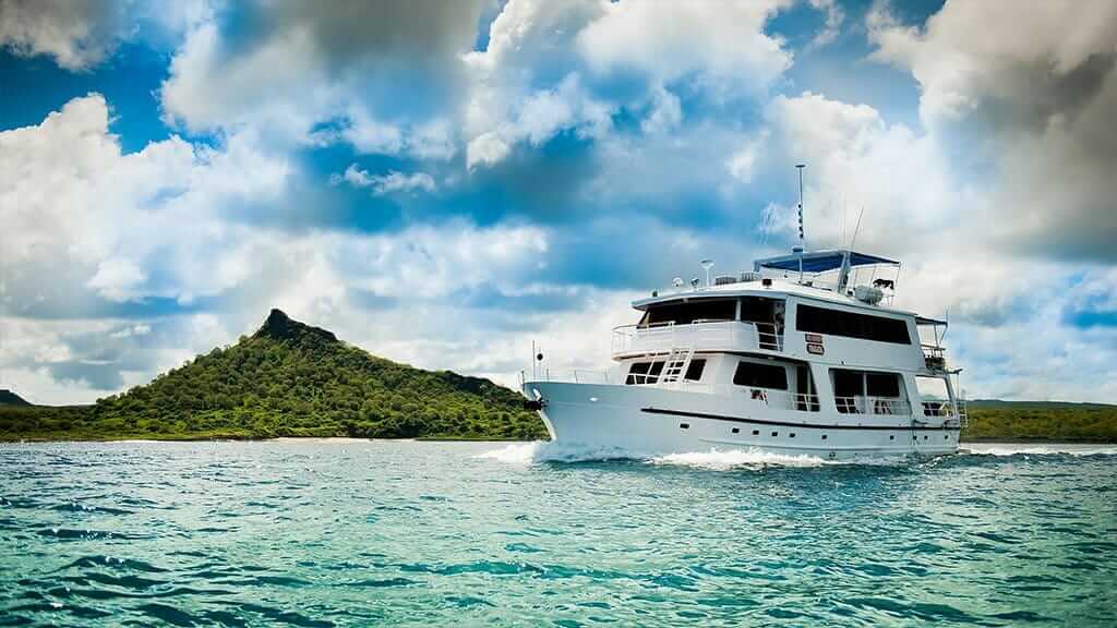 Fragata Yacht Cruise Galapagos Island - Seitenansicht der Fragata mit grünem Inselhintergrund