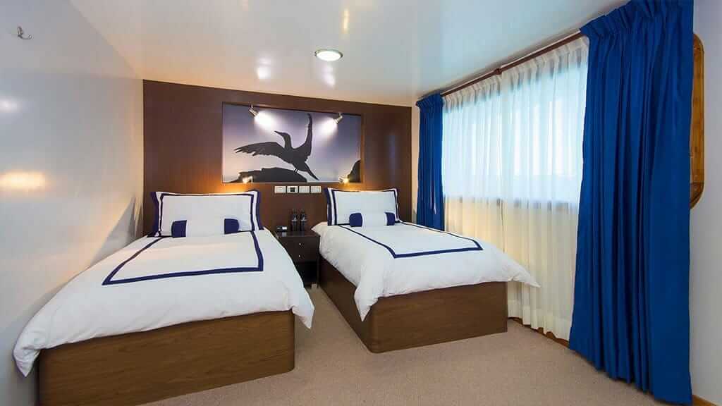 Cabina de invitados con dos camas individuales a bordo del catamarán Ocean Spray en Galápagos