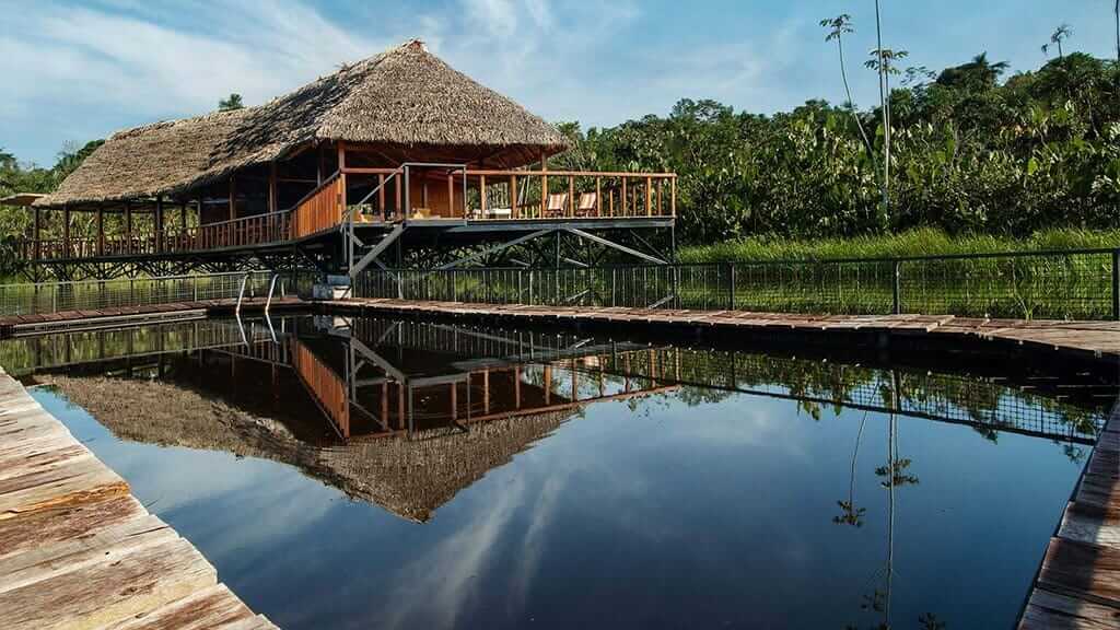 Hoofdgebouw van Sacha Lodge weerspiegelt in het heldere oerwoudwater in de Amazone van Ecuador