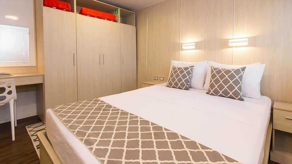 cabina con cama doble y piso de madera a bordo del yate Solaris Galápagos