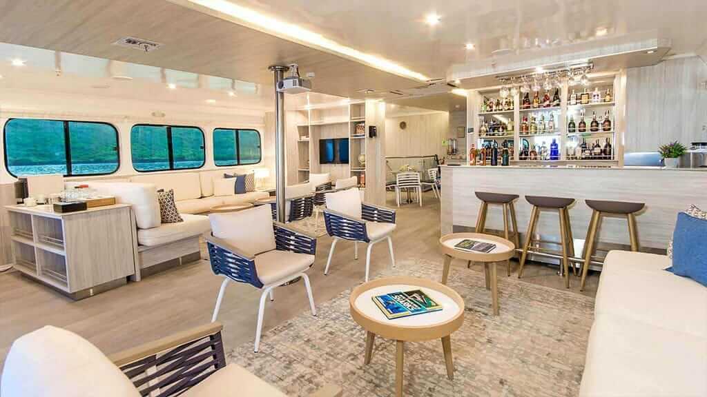 Solaris Yacht Galapagos Cruise Área de salón interior con mesas de café y bar