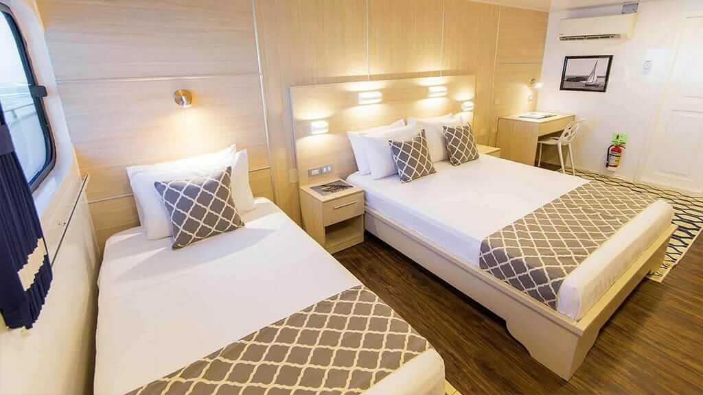 cabina con dos camas individuales y piso de madera a bordo del yate Solaris Galápagos