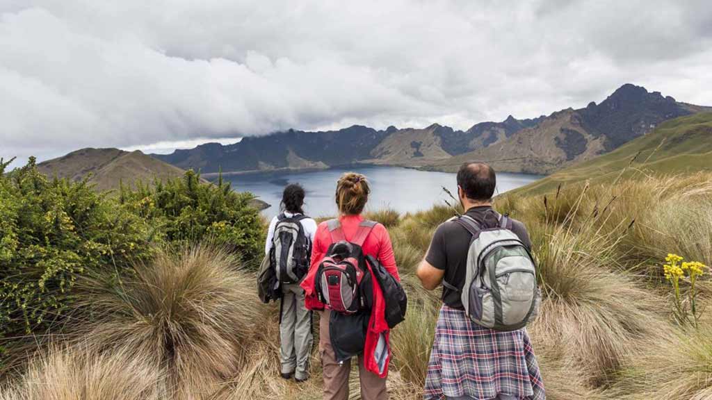 three tourists trek to the lake in ecuador