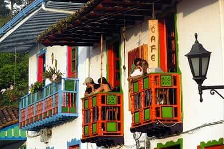 tourists drinking coffee on colorful balconies of the colombia coffee triangle