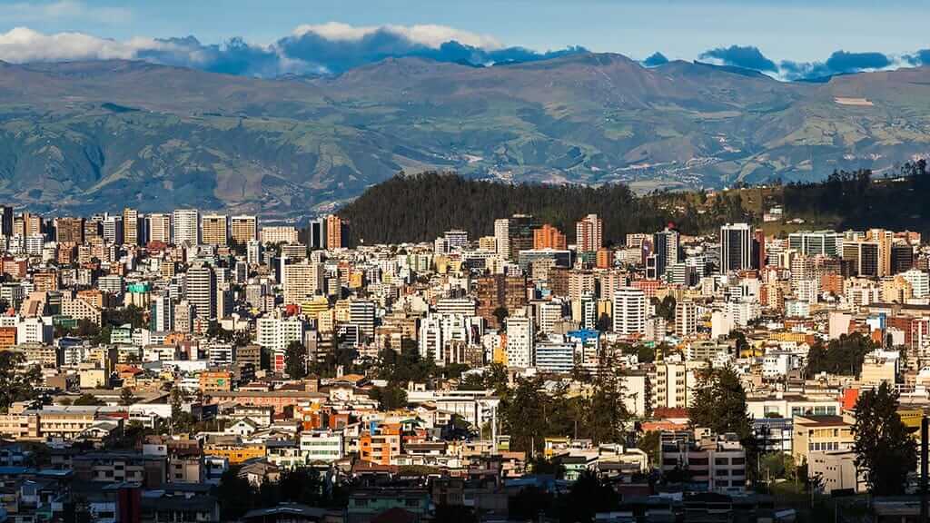 landscape of modern buildings and green mountains of quito city in ecuador