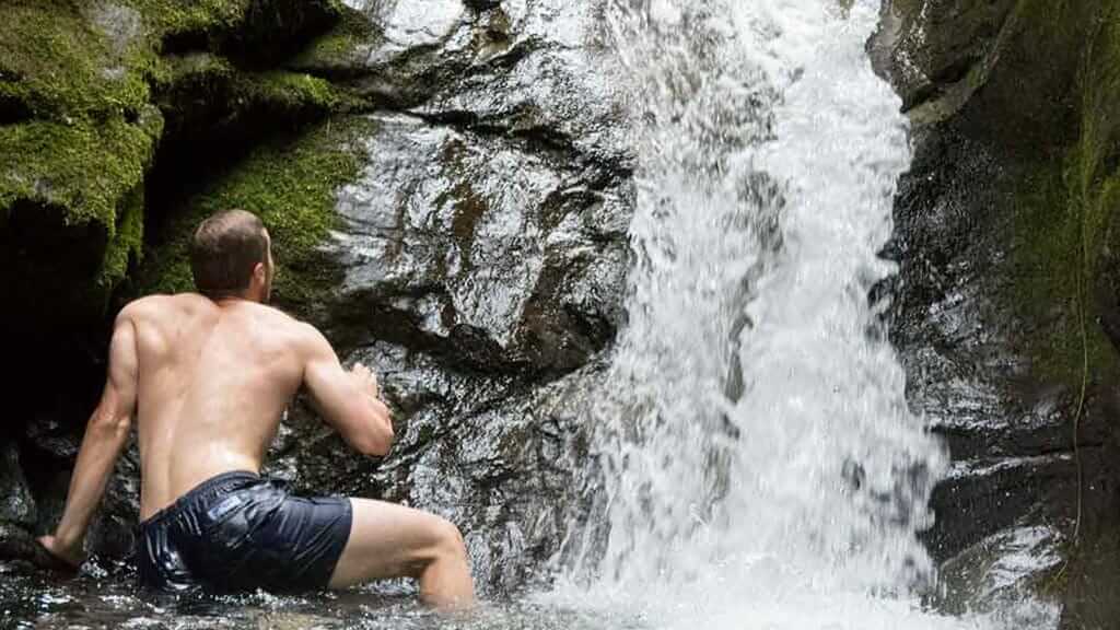 a tourist bathing under a waterfall at mindo ecuador