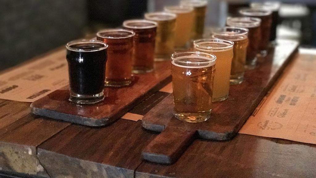 different types of ecuador beer lined up on a wooden platter