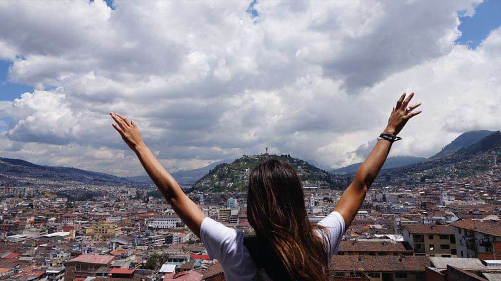 tourists with arms spread wide at panecillo quito ecuador
