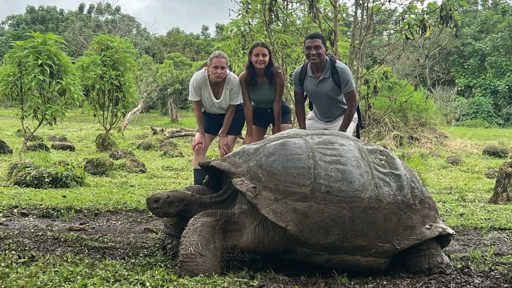 family-with giant tortoise in-galapagos-national park highlands