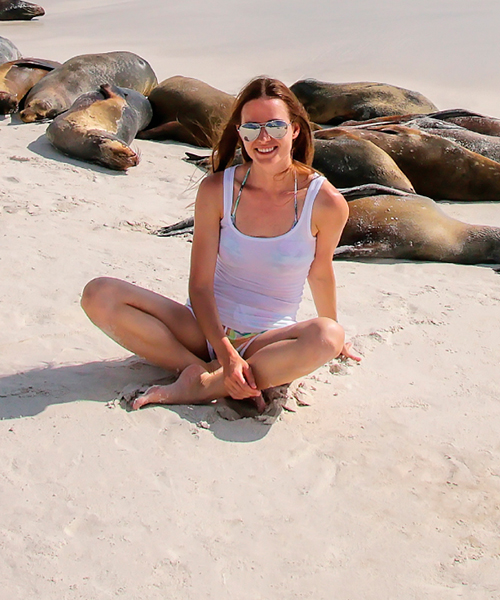 tourist sitting on beach with galapagos sea lions