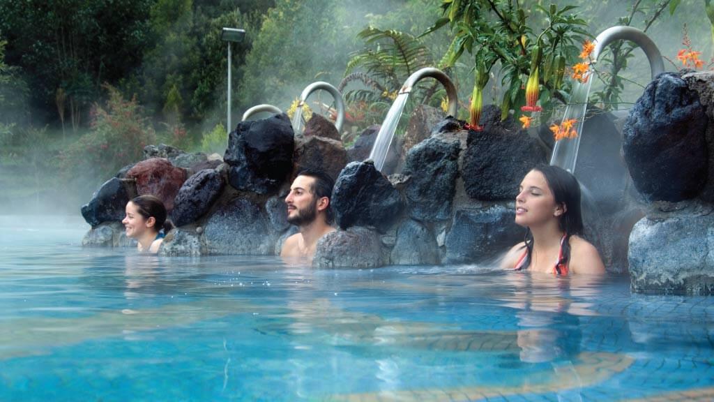 tourists relax under waterfall at papallacta spa resort ecuador