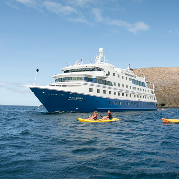 tourists paddle a yellow kayak beside their galapagos cruise ship