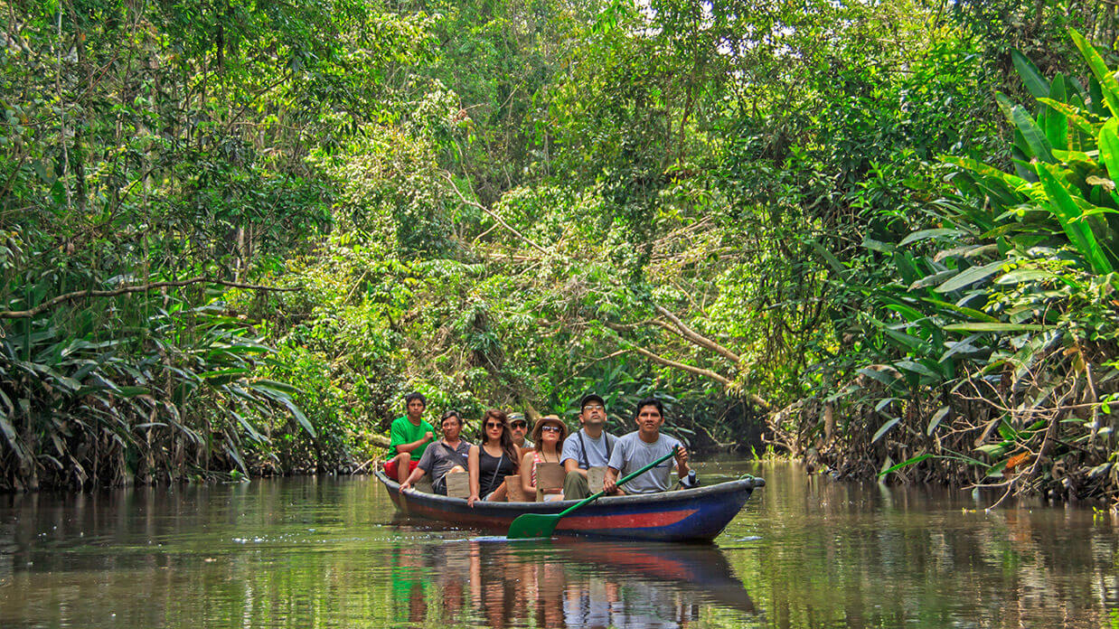 ecuador amazon rainforest canoe ride guide with tourists